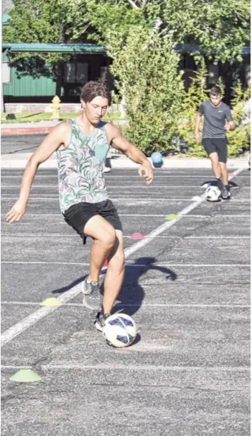  ??  ?? Aza Jaffe (foreground) dribbling around cones in the parking lot during a workout at East Mountain High School. Photo by Ger Demarest.