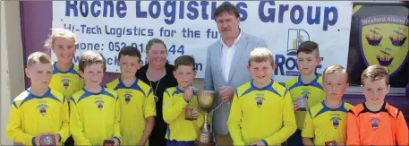  ??  ?? Niall Mooney, the New Ross Town captain, receives Jack’s Cup from tournament sponsor Damien Roche of Roche Logistics Group and the Wexford Albion Chairperso­n, Lynda Dempsey.