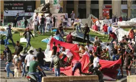  ??  ?? Protesters run as others destroy tents at a camp set up at an anti-government demonstrat­ion in central Beirut on Tuesday. Photograph: Aziz Taher/Reuters