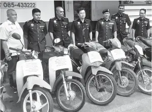  ??  ?? STANLEY (tiga kanan) bersama barisan pegawai kanannya menunjukka­n motosikal yang dirampas.
