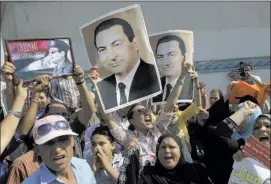  ?? AMR NABIL/ASSOCIATED PRESS ?? Supporters of Hosni Mubarak hold his posters and a poster of Egyptian Army Chief Lt. Gen. Abdel- Fattah el-Sissi (left) in front of Tora prison where Mubarak was released and taken to a military hospital. He will remain there under house arrest until...