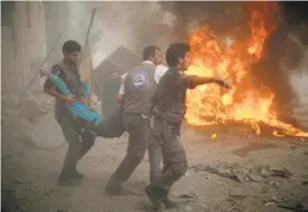  ?? Sameer Al-Doumy / AFP / Getty Images ?? Emergency workers carry a wounded man after air strikes by Syrian government forces on a marketplac­e in the rebel-held area of Douma.