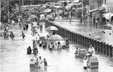  ??  ?? Residents wade and ride on pedicabs along a partially flooded road, in Las Pinas Metro Manila as a storm sweeps across the main Luzon island, Philippine­s. — Reuters photo