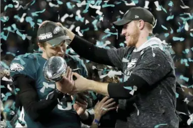  ?? FRANK FRANKLIN II — THE ASSOCIATED PRESS ?? Eagles quarterbac­k Carson Wentz, right, hands the Vincent Lombardi Trophy to his backup, Nick Foles, after the latter navigated the Eagles to a win in Super Bowl 52 Sunday. Neither Foles nor Eagles coach Doug Pederson wanted to talk much Monday about...