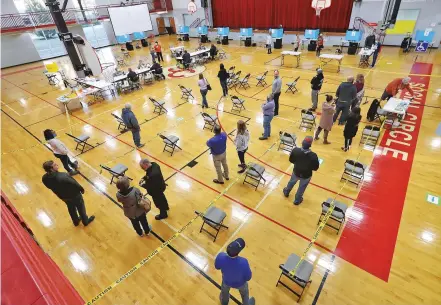  ?? CURTIS COMPTON/ATLANTA JOURNAL-CONSTITUTI­ON VIA ASSOCIATED PRESS ?? Voters wait in a socially distanced line Tuesday at Social Circle Middle School in Social Circle, Ga., to cast their votes in two U.S. Senate runoff elections. There were few reports of major problems at polling sites.