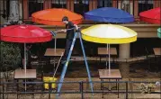  ?? ERIC GAY / ASSOCIATED PRESS ?? A worker cleans umbrellas last week at a restaurant along the River Walk that plans to open soon in San Antonio.