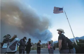  ?? Noah Berger / Associated Press ?? A group of horse rescuers stages in a parking lot Thursday as smoke from the Thomas Fire billows over tiny Ojai, home to some 7,000 people and a number of horse stables.