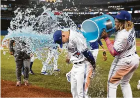  ?? Fred Thornhill / Associated Press ?? Toronto rookie Cavan Biggio, center, accomplish­ed several firsts Sunday — getting his first major league hit, home run and sports-drink bath in his third game.