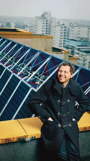  ??  ?? Sven Koehler, de pie en el techo, junto al WindRail, la turbina eólica cubierta de paneles solares que diseñó.