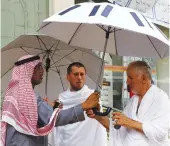  ?? AFP ?? Saudi engineer Kamel
Badawi, left, demonstrat­es the use of his invention, the smart umbrella, which uses solar energy to cool the user.