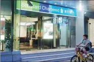  ?? PROVIDED TO CHINA DAILY ?? A customer rides past an outlet of Standard Chartered Bank in Shanghai.