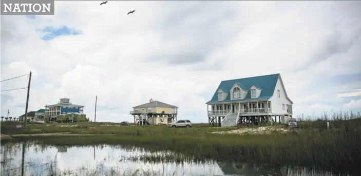  ?? Nicole Craine / Bloomberg ?? Houses sit along the flood zone in Dauphin Island, Ala., about 400 miles east of Houston. Communitie­s need to build with climate-created extremes in mind.