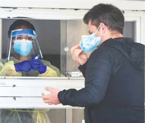  ?? RYAN REMIORZ / THE CANADIAN PRESS ?? A man removes his face mask before being tested for COVID-19 at a Montreal clinic on Friday. Until an effective antiviral drug to treat the coronaviru­s is developed, society’s best strategy is to avoid catching the disease.