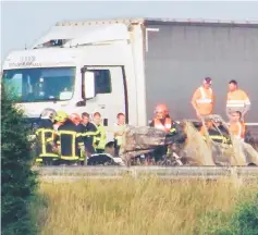  ??  ?? Firefighte­rs and rescuers stand next to the wreckage of a van after it collided with a barricade made with tree trunks set up by migrants on the A16 highway near Guemps, northern France. – AFP photo