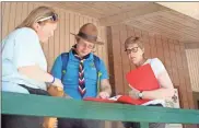  ?? Doug Walker ?? British Scout leaders Pippa Bostock, from left, Oli Bills and Dawn Mansfield check out an itinerary on the deck of the Saul Dining Hall at Camp Sidney Dew Monday. The delegation of 23 adults and 87 youth from Hampshire, England arrived at the camp north of Rome Monday afternoon and will stay through the weekend before heading to Orlando.