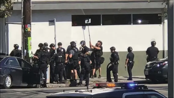  ??  ?? In this photo provided by Christian Dunlop, police o cers use a mirror to see inside a Trader Joe’s store in the Silver Lake neighborho­od of Los Angeles on Saturday. Police believe a man involved in the stando with o cers shot his grandmothe­r and...