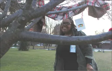  ?? Photos by Patricia Martin ?? Staff from the Community Health & Wellness Center in Torrington spread warmth in the form of scarves, free for the taking, on fenceposts and street signs near the downtown area earlier this week. Above, “Elf” Tasha Laviera ties scarves on trees in Coe...