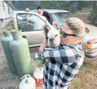  ??  ?? Sheleigh Knight prepares to leave Killarney with her father, Rob Joll, and their dog on Tuesday after evacuation­s were ordered.