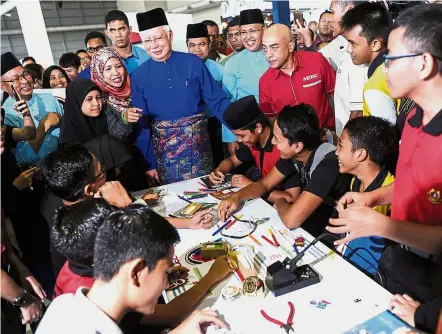  ??  ?? People’s leader: Najib sharing a light moment with some youths during the launch of the Langkawi Digital Carnival at Mahsuri Internatio­nal Exhibition Centre (MIEC). — Bernama