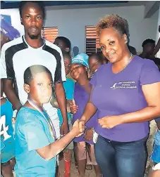  ??  ?? Event organiser Tynesa Miller (right) makes a presentati­on to a participan­t at the Kidz Connection Football Jamboree at Duhaney Park field recently.