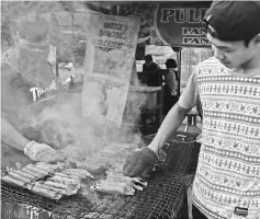  ??  ?? The siblings grill their popular ‘pulut panggang’ at their stall in Sibu Town Square Phase 2.