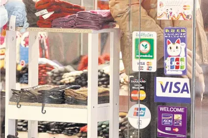  ?? THANARAK KHUNTON ?? Stickers showing a variety of credit cards accepted are displayed on the door of a shop in Bangkok. Authoritie­s expect credit card use to rise this year as the e-payment system takes root.