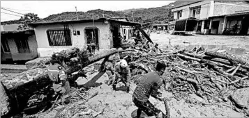  ?? FERNANDO VERGARA/AP ?? Rescuers search Sunday for survivors in Mocoa, Colombia, where heavy rain led to flooding of three rivers that surround it.