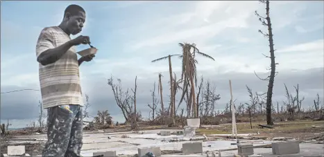  ?? RAMON ESPINOSA/AP ?? Jeffrey Roberts, 49, eats at his relatives’ destroyed home on Grand Bahama.