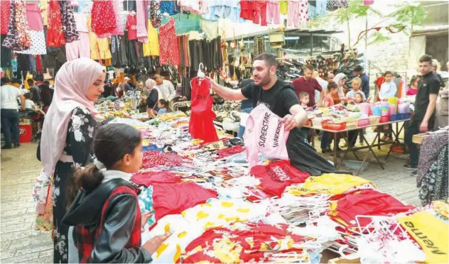  ?? Agence France-presse ?? ↑
Palestinia­ns shop at a market in the old city centre of Hebron in West Bank, ahead of Eid Al Fitr, on Saturday.