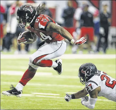  ??  ?? Falcons running back Devonta Freeman eludes the reach of Texans safety Quintin Demps during last week’s 48-21 victory. Freeman is the first player since 1970 to record three rushing touchdowns in each of his first two starts.