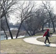  ?? (NWA Democrat-Gazette/Andy Shupe) ?? A resident walks past the White River along a trail in Bunch Park in Elkins Wednesday. The city of Elkins received $95,000 to build a mini prairie nearby that will provide source water protection, restore wildlife, prevent sediment from entering the White River and provide opportunit­ies for recreation.