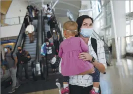  ?? DAI SUGAN0— STAFF PHOTOGRAPH­ER ?? Sarah Clark, holding her 19-month-old daughter, Emilia, arrives at Norman Y. Mineta San Jose Internatio­nal Airport on Monday.