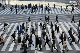  ?? KOJI SASAHARA — THE ASSOCIATED PRESS ?? People wearing face masks to protect against the spread of the coronaviru­s cross an intersecti­on on a street in Tokyo, Wednesday.