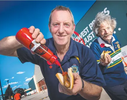  ??  ?? Ian Nicholls and Peter O'Brien get stuck into a sausage sandwich at a Bunnings store. Picture: Tony Gough