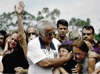  ?? Mateus Bonomi/Folhapress ?? Parentes de João Pedro Calembo, morto a tiros por colega de sala na última sexta-feira, se abraçam durante sepultamen­to do adolescent­e no cemitério Parque Memorial de Goiânia, na manhã de ontem