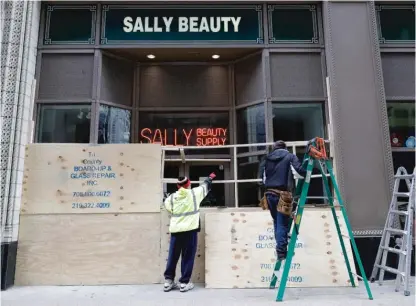  ?? NAM Y. HUH/AP ?? Workers board up at Sally Beauty in downtown Chicago on March 22.