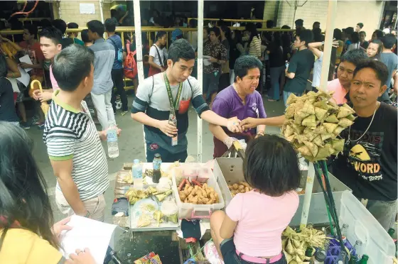  ?? (SUN.STAR FOTO/ARNI ACLAO) ?? Applicants waiting to be registered for the youth and barangay elections in October buy their lunch from a food cart outside the Cebu City Comelec office.