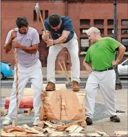  ?? DANA JENSEN/THE DAY ?? Patxi Gandigia, right, of Manchester looks back to see how close the log is to splitting while he and Riki Lasa, left, of East Granby support the log so Jon Aramendi, center, of Lebanon doesn’t fall when the final cut is made while demonstrat­ing endurance wood-cutting during the Basque Fest on Parade Plaza in New London on Saturday. The festival was hosted by the New England Basque Club.