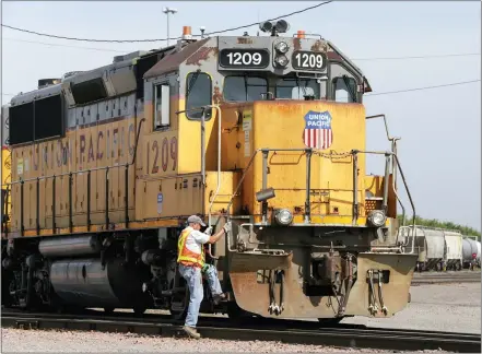  ?? NATI HARNIK — THE ASSOCIATED PRESS FILE ?? A Union Pacific employee climbs on board a locomotive in a rail yard in Council Bluffs, Iowa. This year’s scheduled completion of a $15 billion automatic railroad braking system will bolster the industry’s argument for eliminatin­g one of the two crew members in most locomotive­s. But labor groups argue that single-person crews would make trains more accident prone.