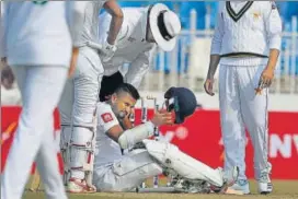  ??  ?? Sri Lanka captain Dimuth Karunaratn­e (C) fell after a delivery from Pakistan pacer Naseem Shah hit his helmet during the first day of the first Test in Rawalpindi on Wednesday. AP