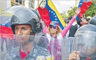  ?? RONALDO SCHEMIDT / AFP ?? Calles. Simpatizan­tes del líder opositor Juan Guaidó se manifiesta­n tras una barrera policial, ayer en Caracas.