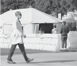  ?? ASHLEYLAND­IS/AP ?? A medical worker passes a tent outside the ER last week atUCI Medical Center in Irvine, California. The state is searching for nurses, doctors and other medical stafftomee­t demands as the coronaviru­s surge pushes hospitals to the breaking point.