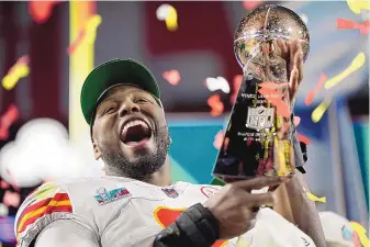  ?? ASHLEY LANDIS/ASSOCIATED PRESS ?? Kansas City defensive end Carlos Dunlap celebrates with the Vince Lombardi Trophy after his Chiefs defeated Philadelph­ia 38-35 in Sunday’s Super Bowl LVII in Glendale, Arizona.