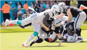  ?? LYNNE SLADKY/ASSOCIATED PRESS ?? Miami defensive end William Hayes (in white) tore his right ACL on this sack of Oakland quarterbac­k Derek Carr because he moved awkwardly in hopes of avoiding a penalty.