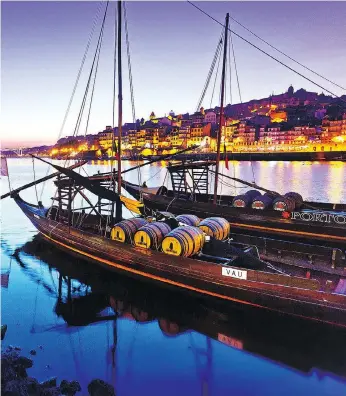  ?? DOMINIC ARIZONA BONUCCELLI ?? Traditiona­l rabelo boats, which were once used to deliver port wine from the Douro Valley, line the brightly lit harbour of Porto, Portugal, at sunset.