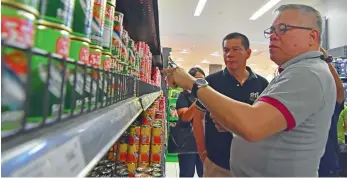  ?? MACKY LIM ?? PRICE WATCH. Trade Secretary Ramon Lopez together with DTI 11 Assistant Regional Director Edwin Banquerigo inspects prices of basic commoditie­s inside a supermarke­t at a local mall in Davao City yesterday. Lopez said after the inspection that prices in...