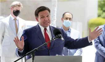  ?? AP; BELOw, gETTy iMagES fiLE ?? NOT LOOKING GOOD: Florida Gov. Ron DeSantis gives an update on the state’s response to the coronaviru­s pandemic on Friday. Below, beachgoers sunbathe in Miami Beach on June 16.