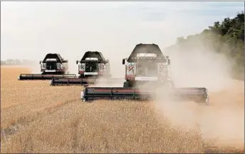  ?? ANDREY RUDAKOV/BLOOMBERG NEWS ?? Harvesters drive through a field of wheat during the summer harvest on a farm in Russia.