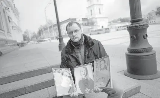  ?? LYNSEY ADDARIO/THE NEW YORK TIMES ?? Serhiy Perebyinis holds portraits of his wife, Tetiana, and his children, Mykyta, 18, and Alisa, 9, who were killed by Russian mortar fire on March 6.