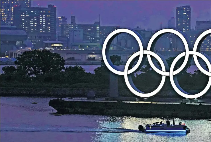  ??  ?? Lights out? The Olympic rings shimmer in Tokyo while athletes, including Dina Asher-smith (right), await their fate